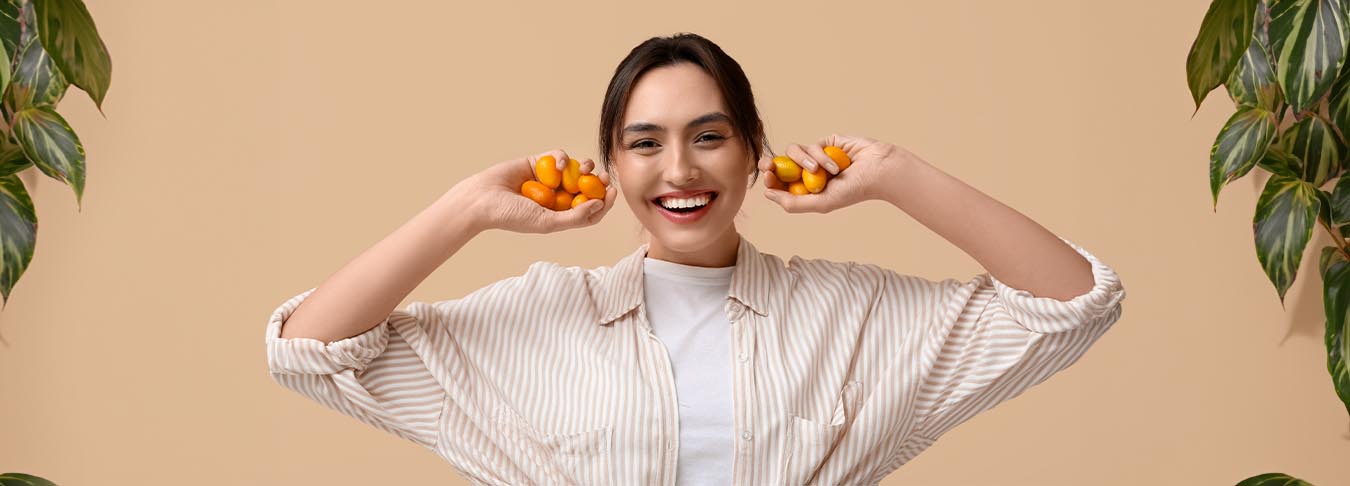 Una persona sosteniendo kumquats en la mano, destacando la frescura y los beneficios antioxidantes de esta fruta.